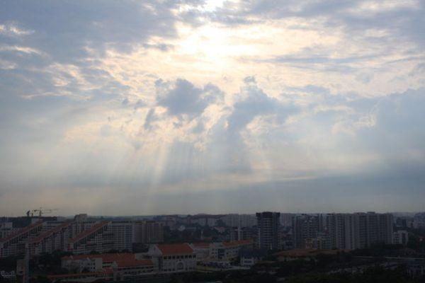 sunrays over clouds above city