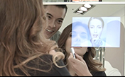 a woman applying makeup and facing the mirror with a man