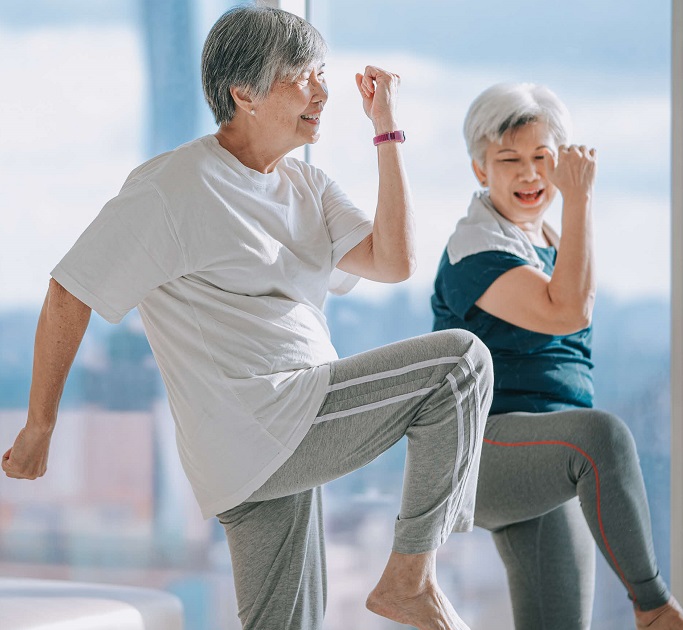 Two senior Asian woman exercising in living room