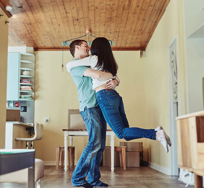 A young man celebrates a moment of happiness with his spouse in their new home