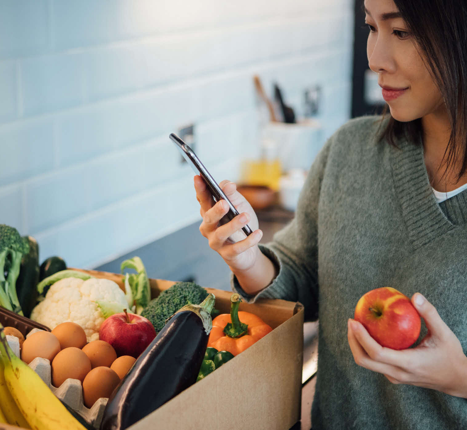 Woman using her smartphone to check her online grocery delivery order