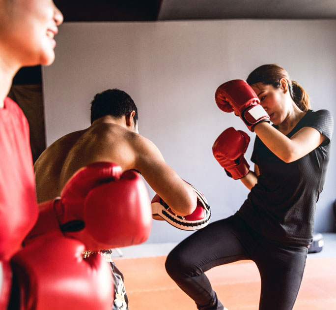 Young woman spars with her muay thai instructor