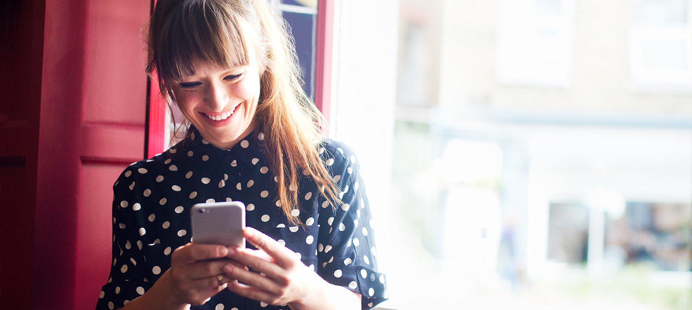 Woman on phone smiling at her long-term investment returns